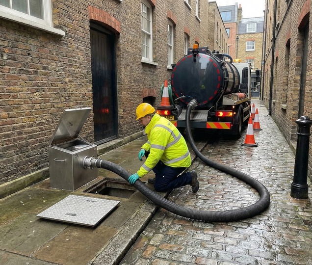 Vacuum tanker operator preparing safe emptying of a grease trap at a service location.