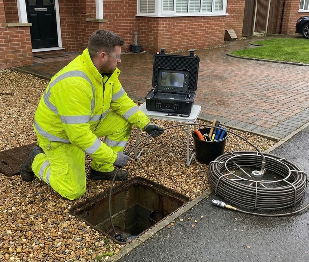 Engineer clearing a blocked domestic drain with professional drainage tools.