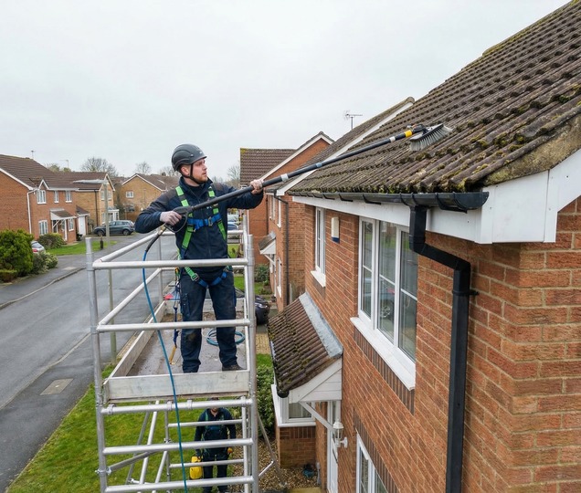 Roof cleaning technician carrying out safe debris and moss removal on a residential property.